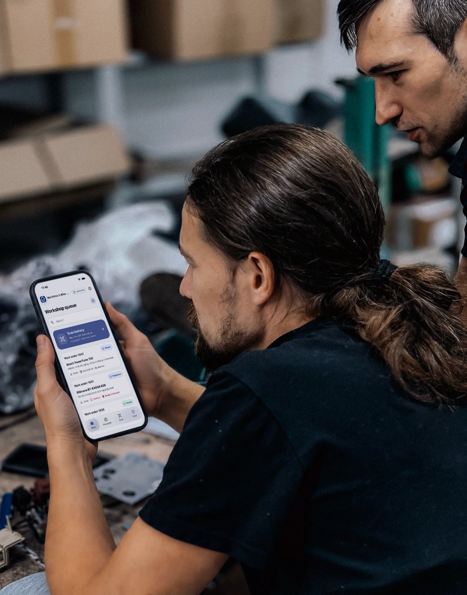 Two battery technicians reviewing diagnostics on a tablet in a professional workshop